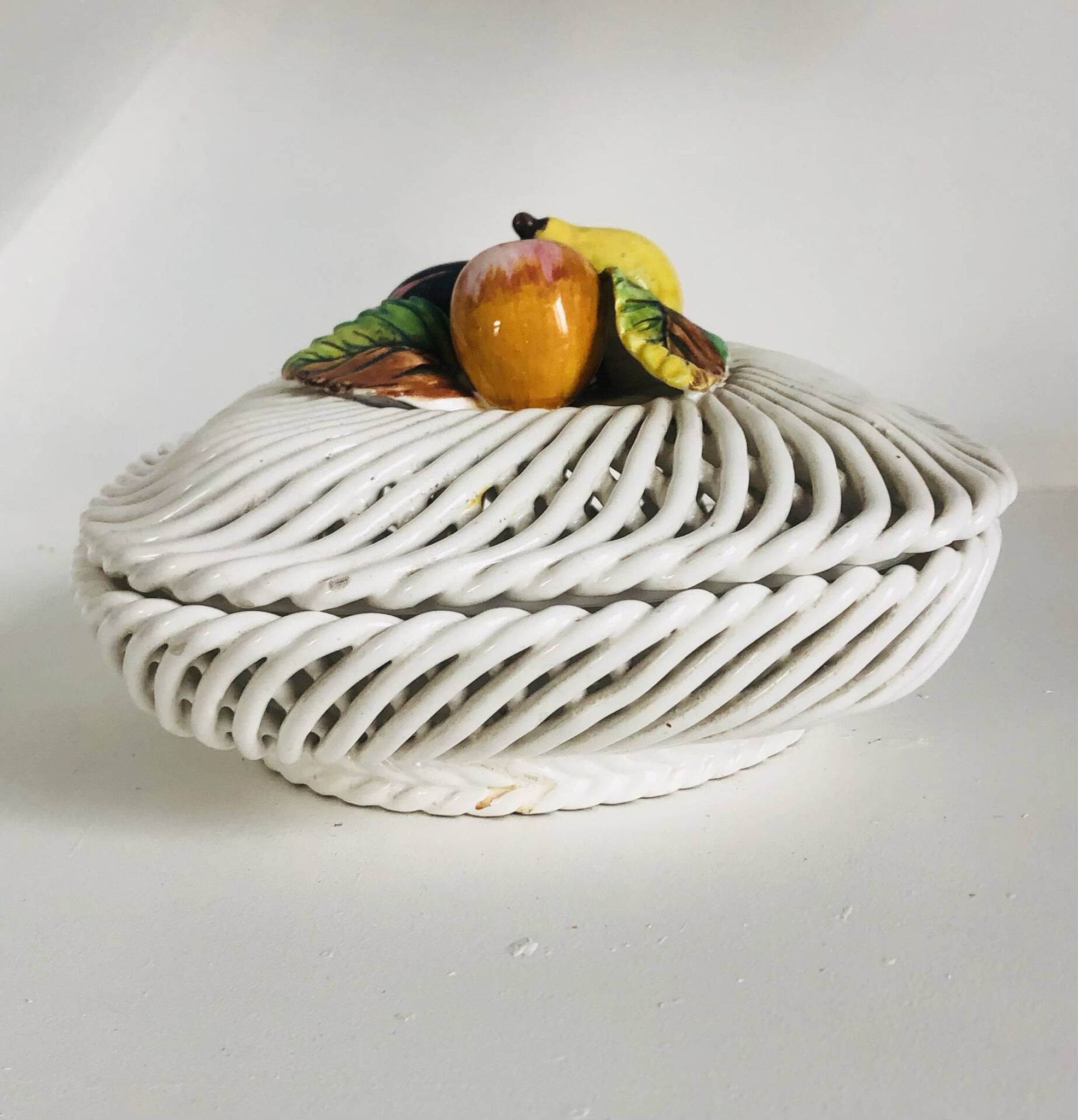 Covered basket in white woven ceramic and fruit slip.