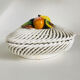 Covered basket in white woven ceramic and fruit slip.