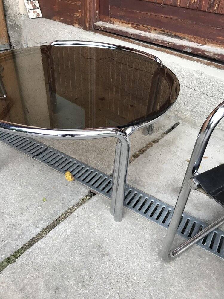 Mid-century round coffee table in chrome and smoked glass with 2 black leather chairs.