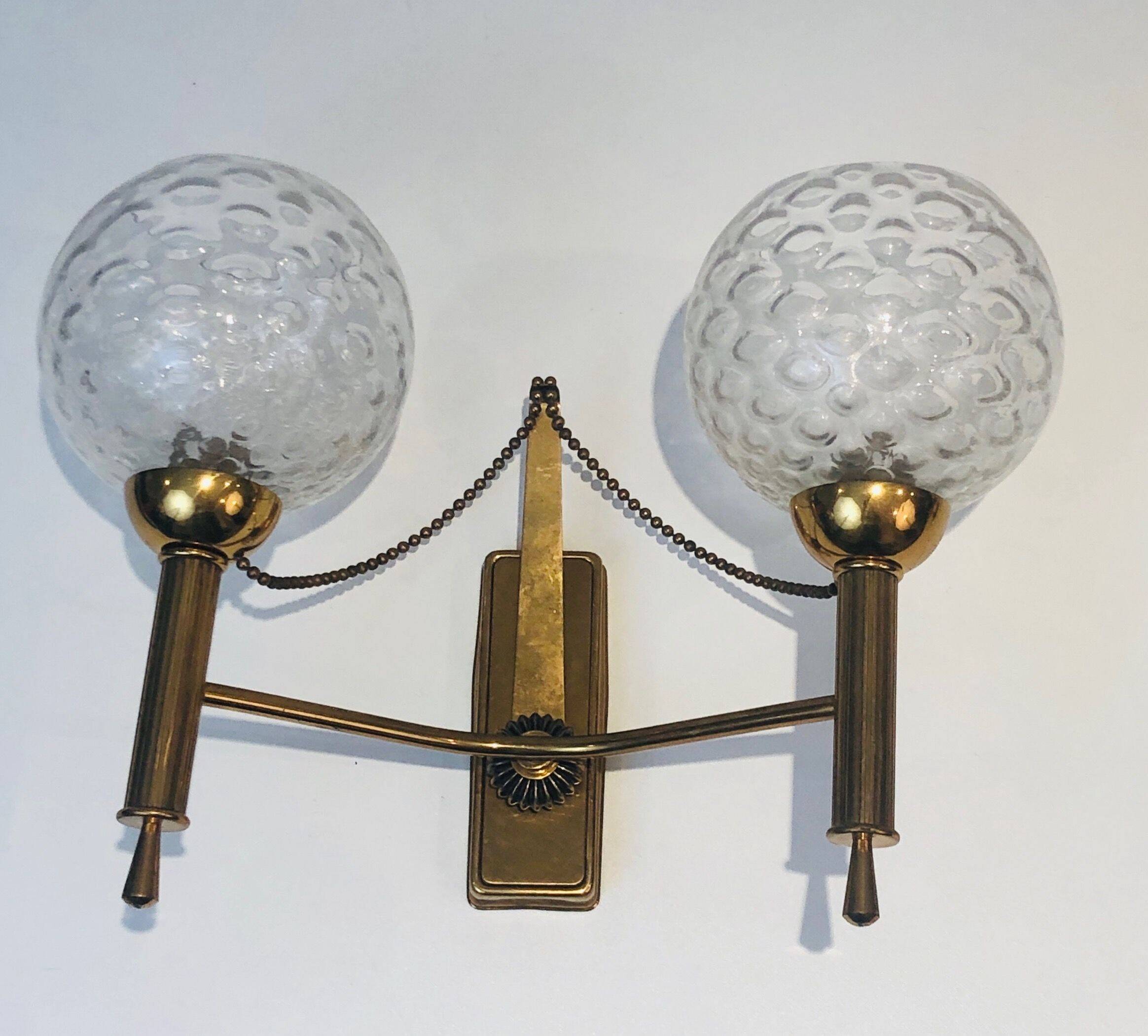Pair of brass wall lights with glass globes. Around 1970.