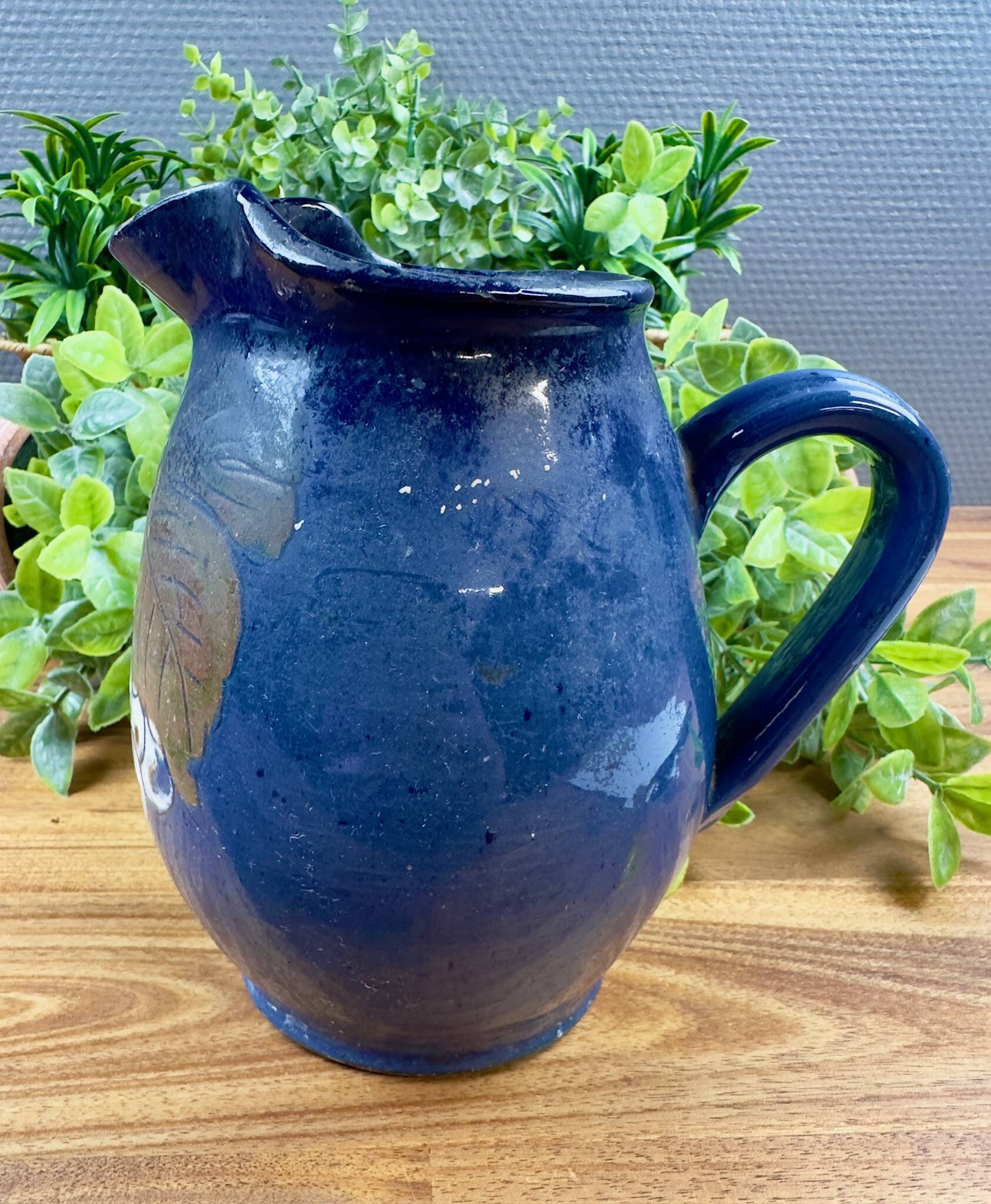 Blue ceramic pitcher with vintage artisan inscription decoration.
