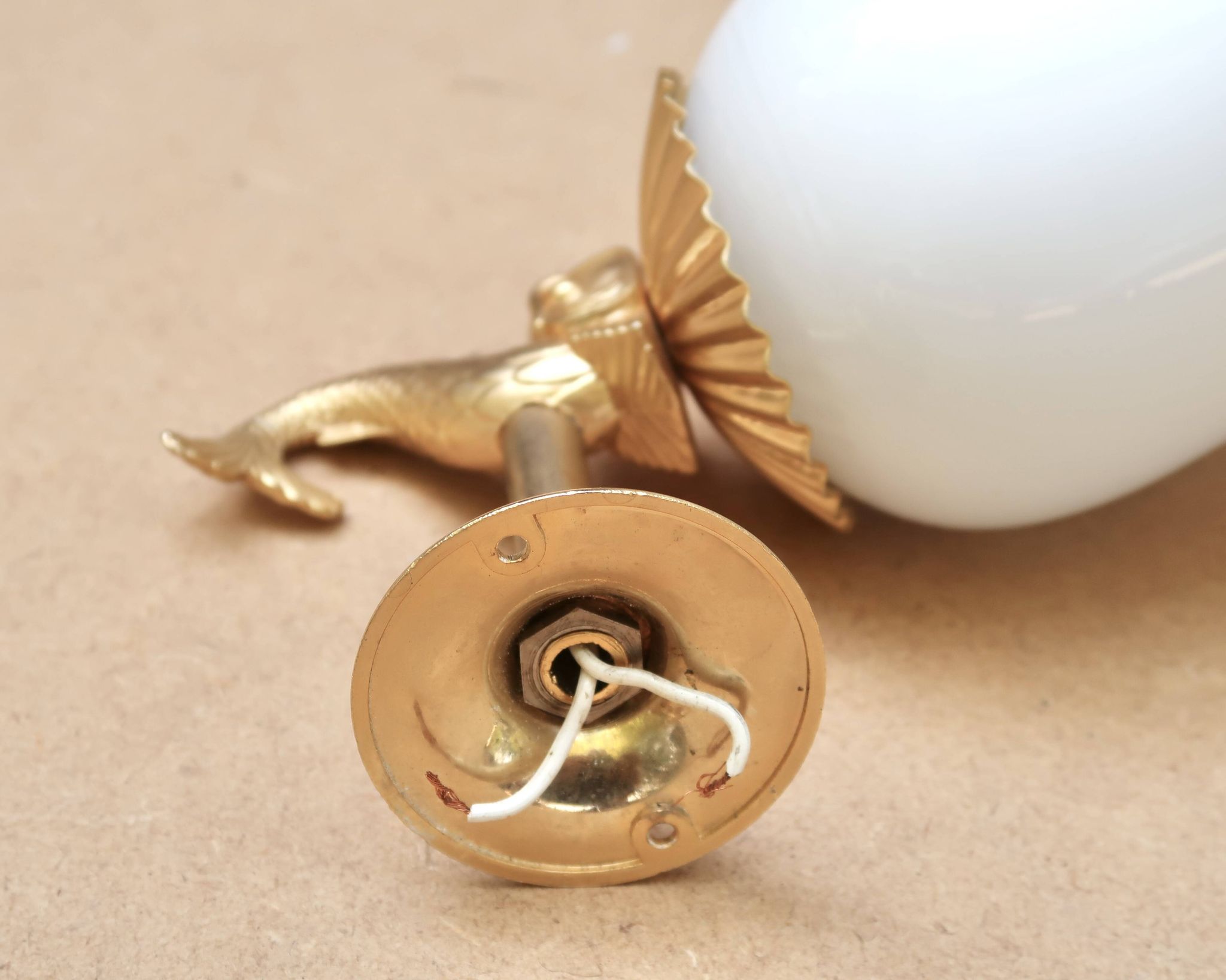 Pair of gold metal and opaque glass wall lights adorned with fish from the 1950s.