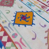 White suzani kilim rug with multi-colored embroidered patterns