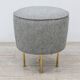 Modern pouf from the Gubi brand in grey fabric and brass.