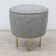 Modern pouf from the Gubi brand in grey fabric and brass.