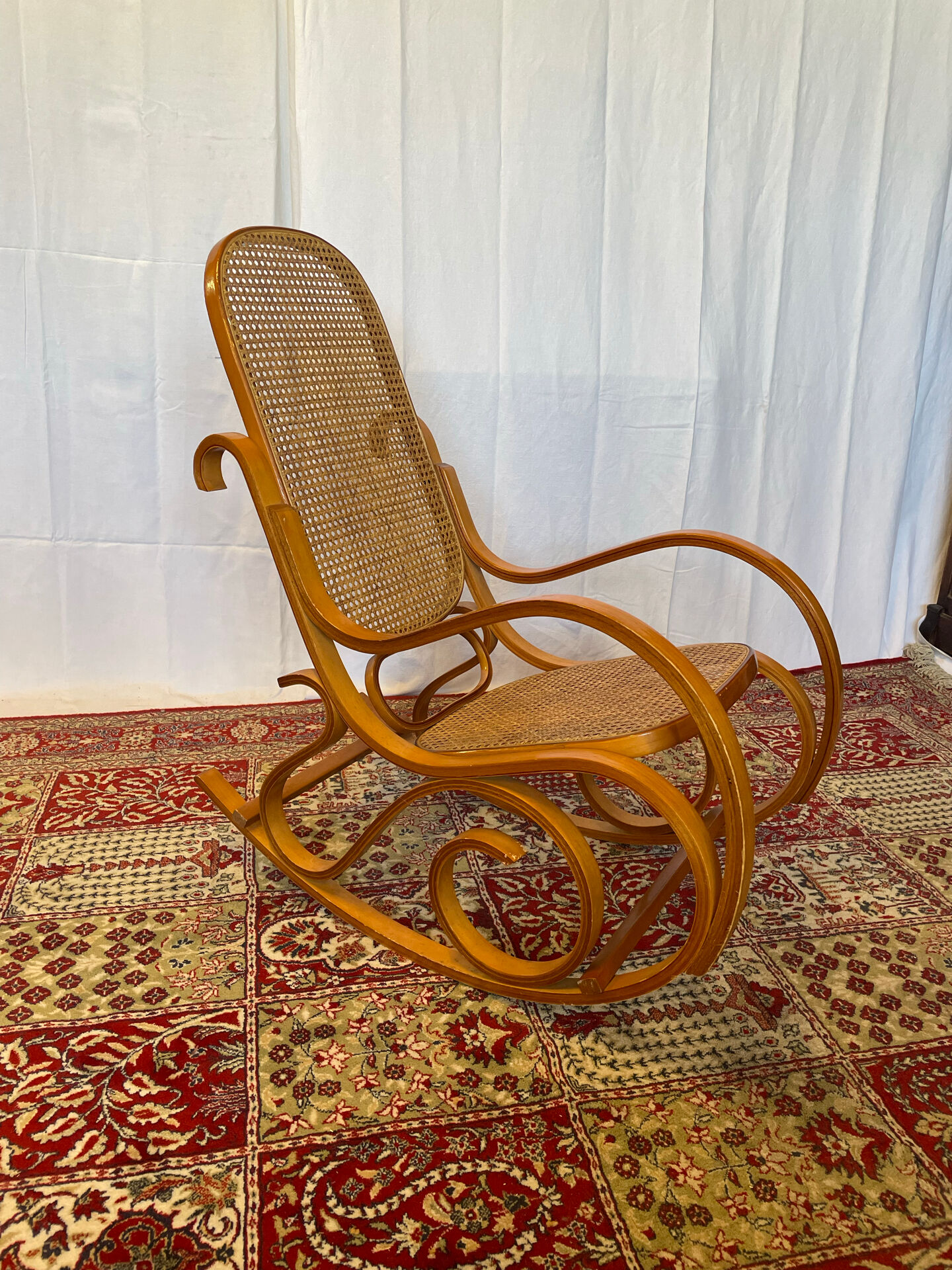 Antique rocking chair in curved wood and caning.