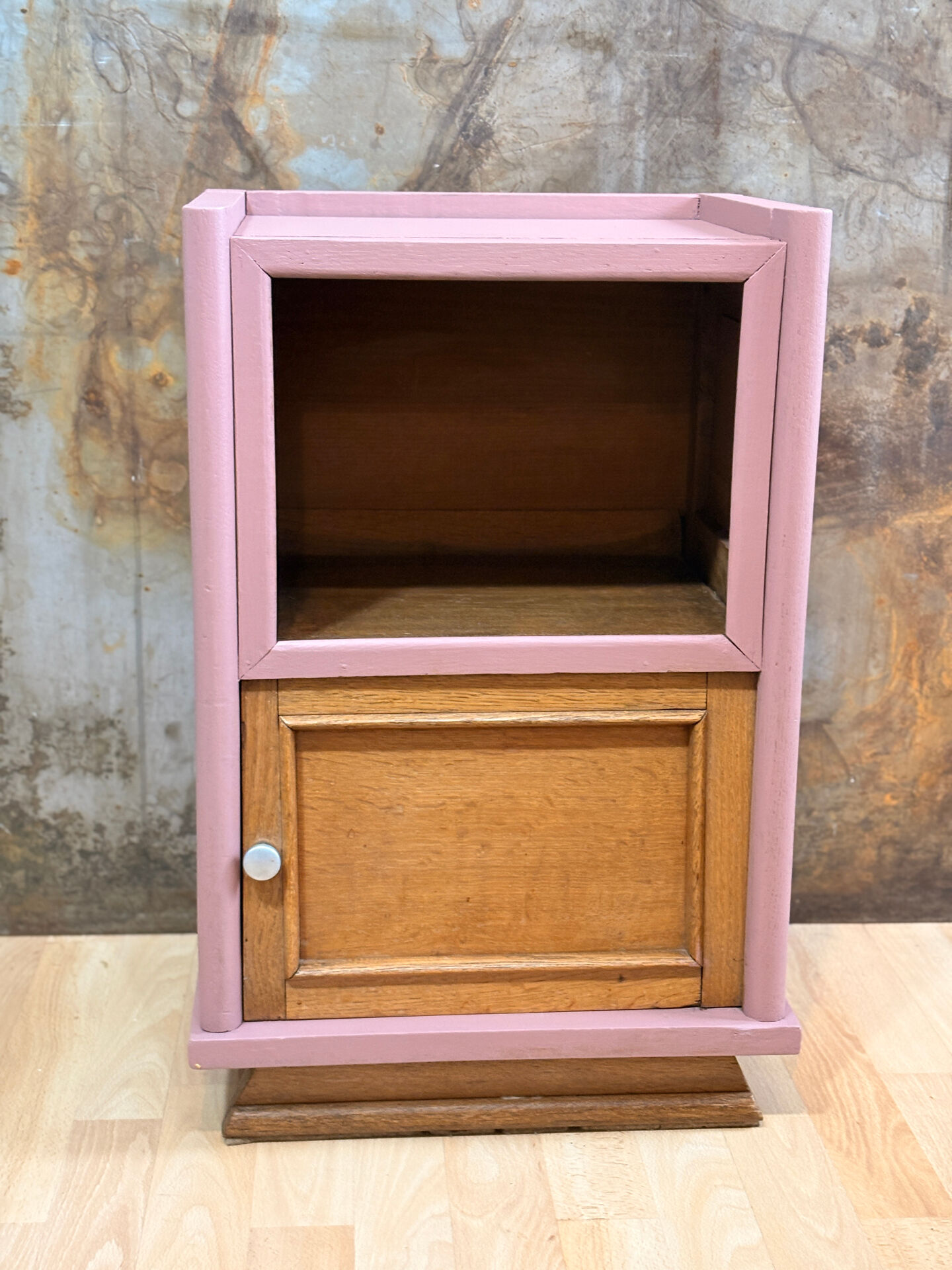 Pink bedside table with haberdashery and raw wood.