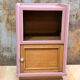 Pink bedside table with haberdashery and raw wood.