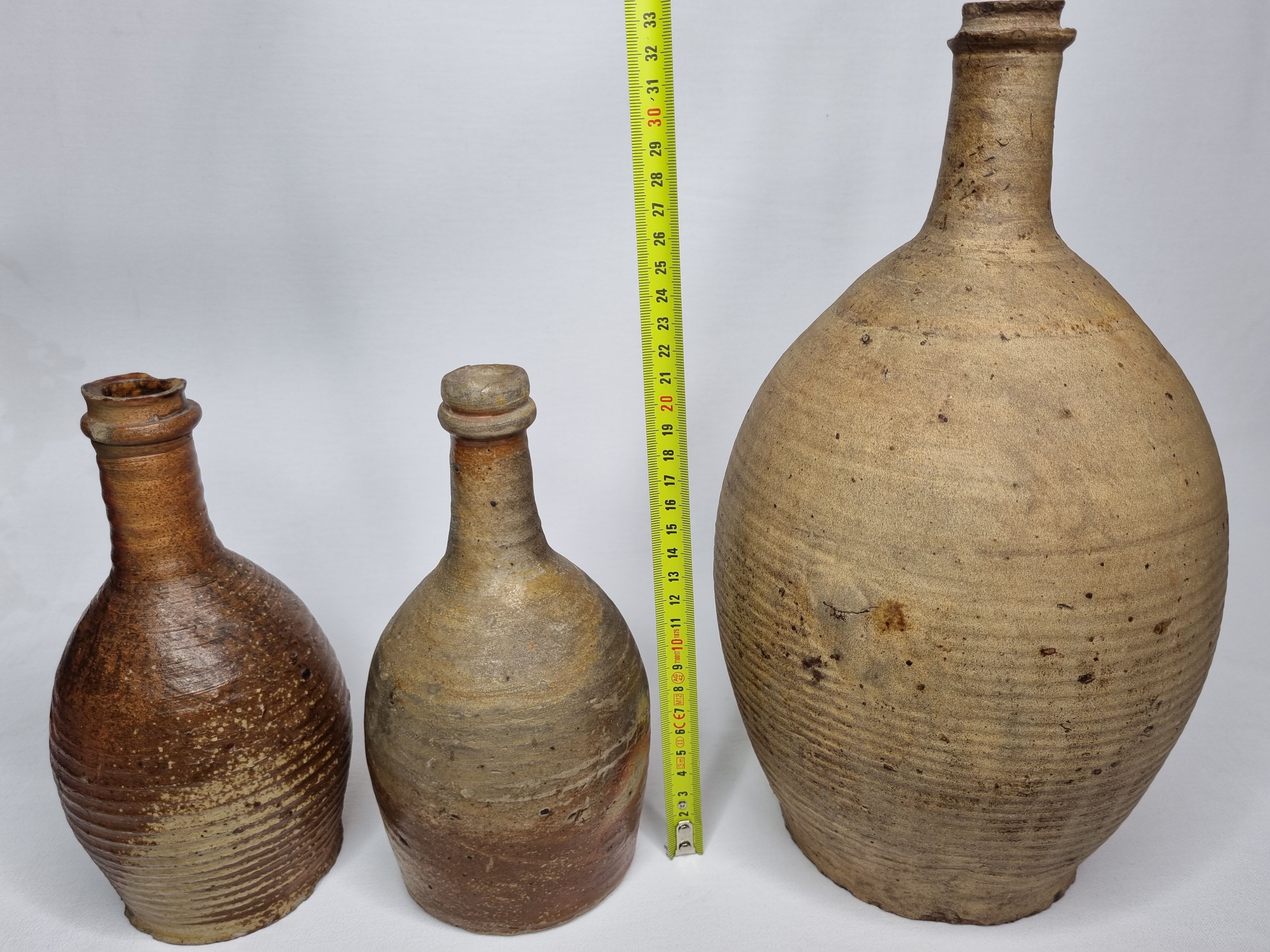 Set of three old enamelled terracotta bottles, 33 cm