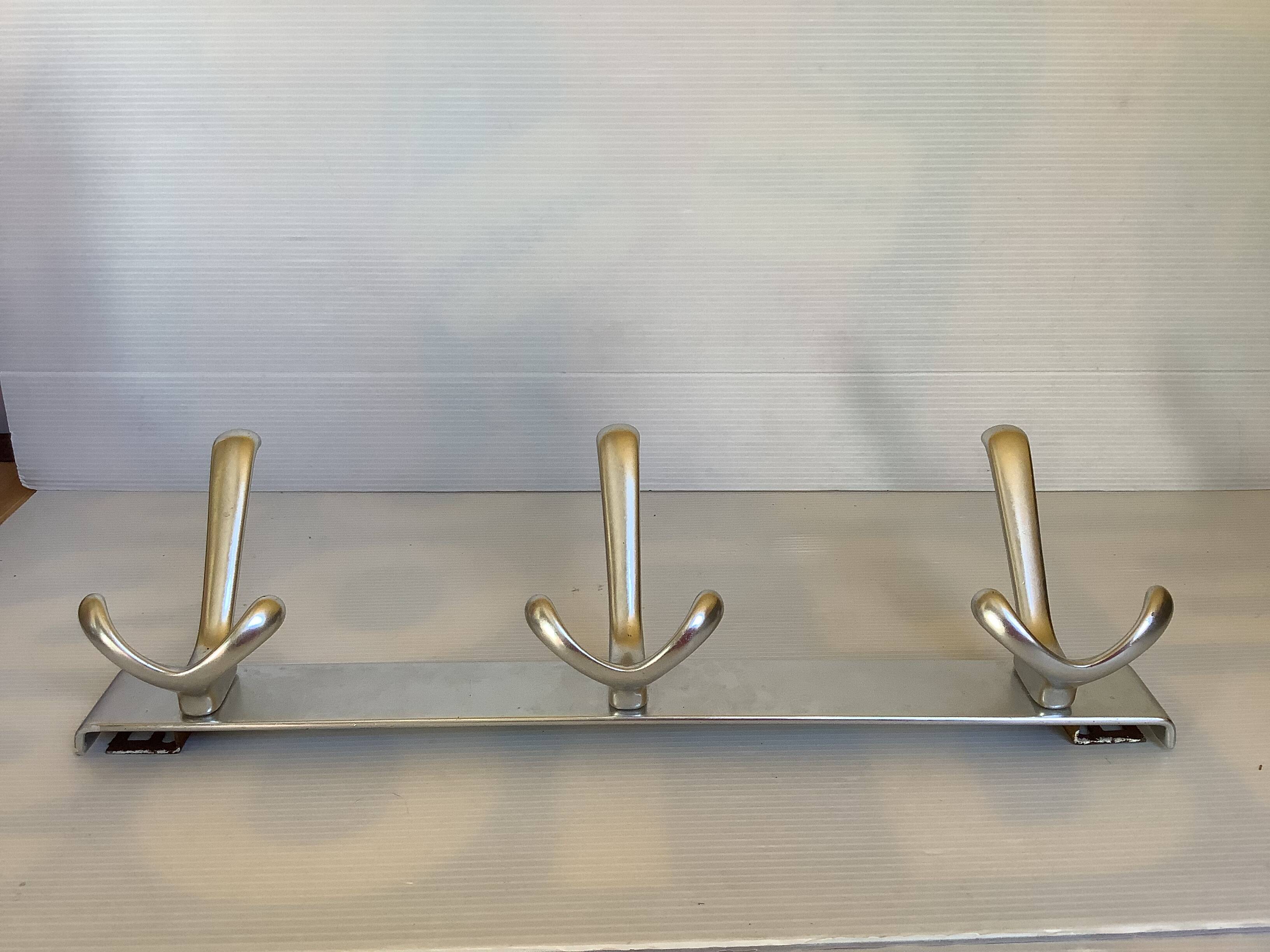 Stainless steel coat rack with three double hooks.