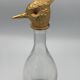Glass bottle type carafe with gold metal bird head stopper