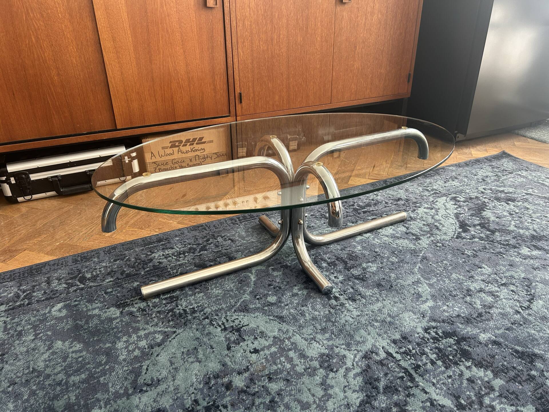 Oval glass coffee table with chrome legs, vintage 70s design.