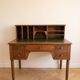 Antique wooden desk with a sloped top and green writing pad.