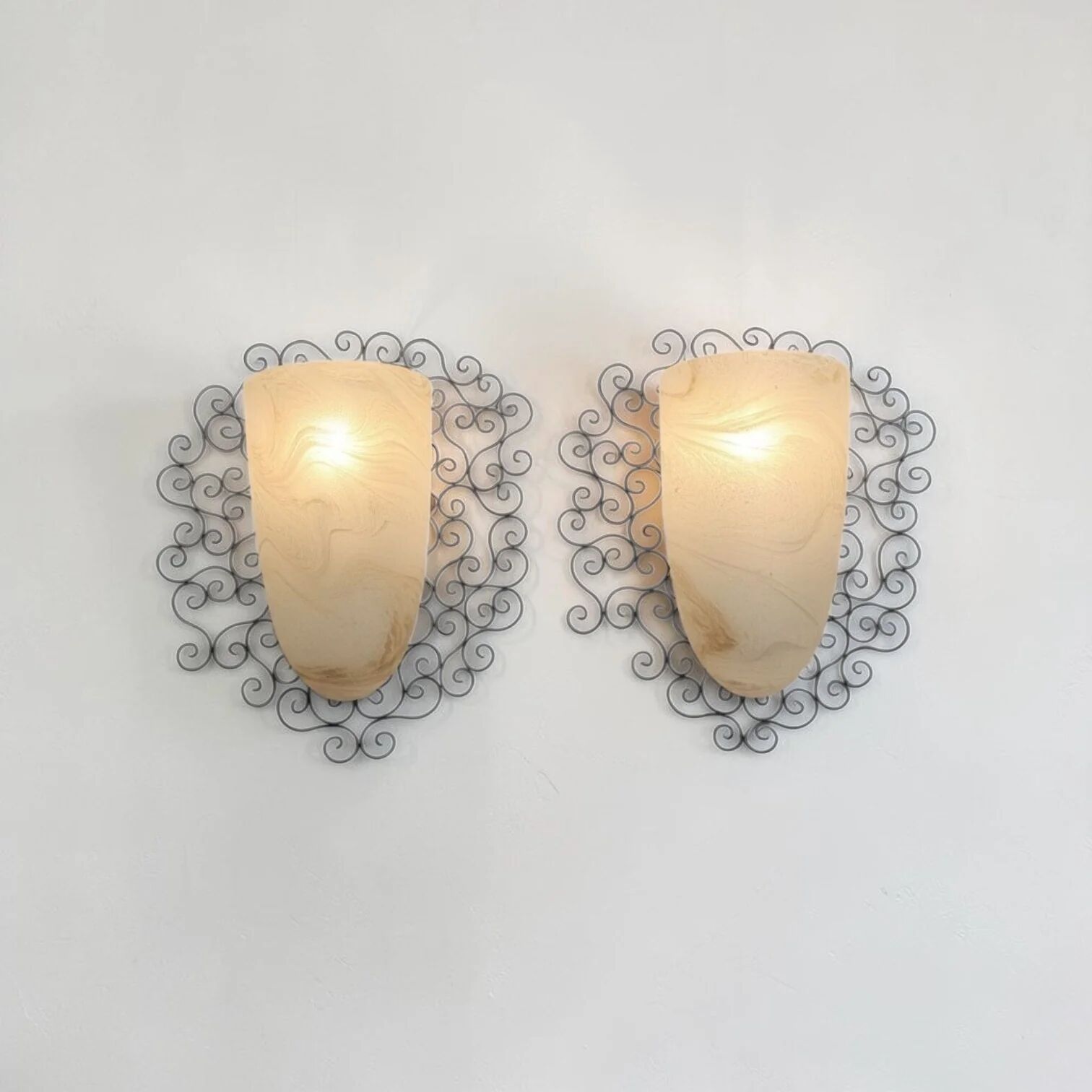 Wrought iron pocket wall sconces featuring a frosted amber glass / metal frame