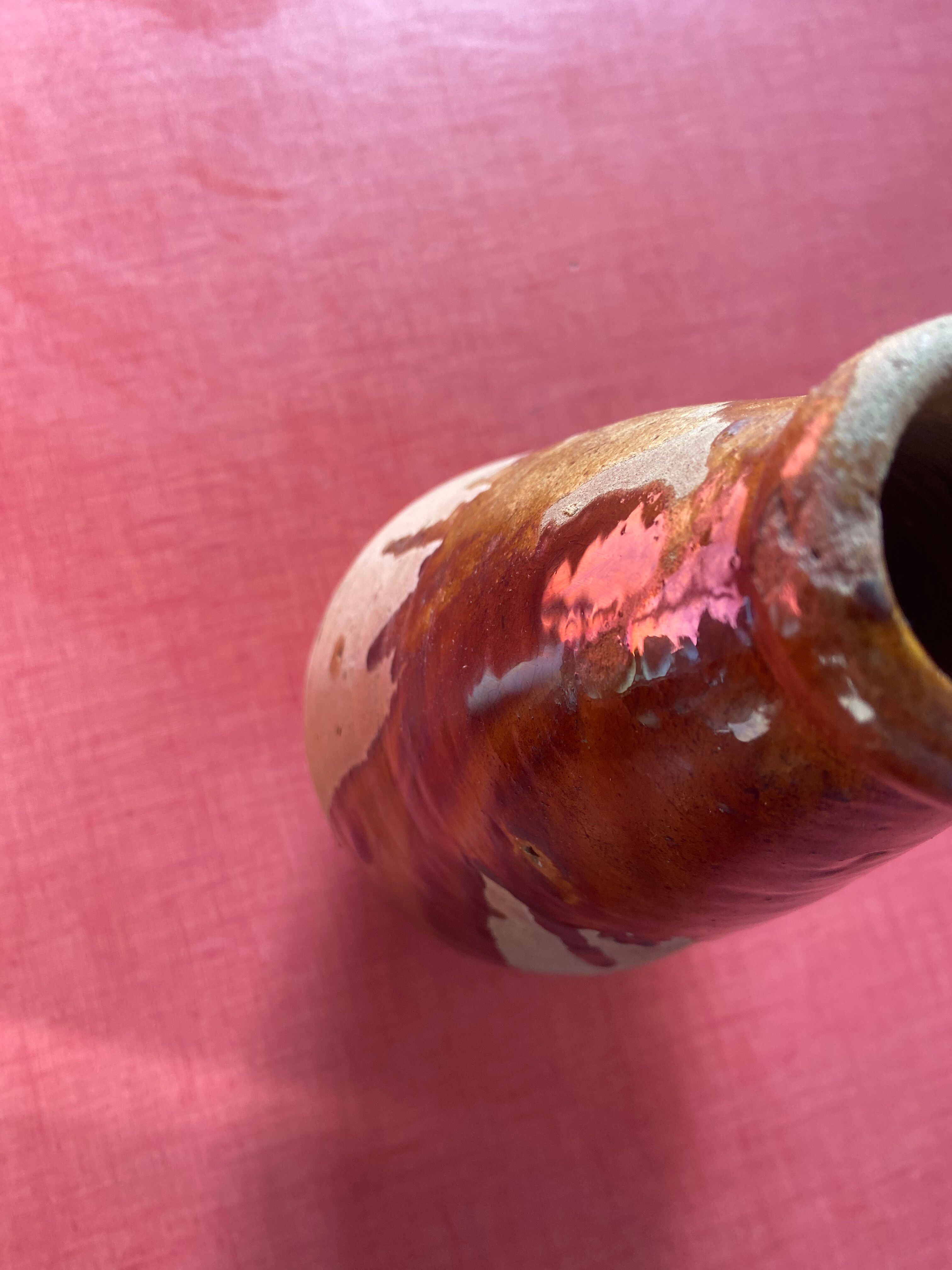 Large antique pottery bottle in glazed terracotta with drips.