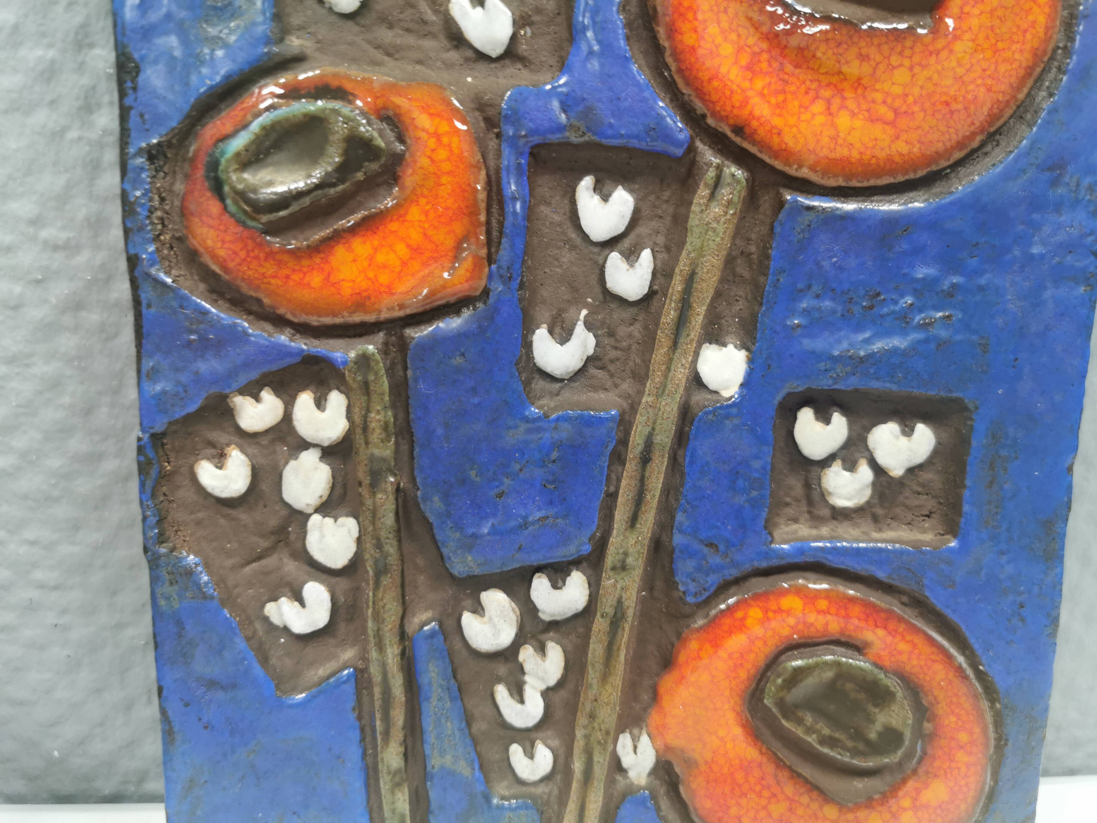 Ceramic relief in attractive blue with a motif of white/red flowers.