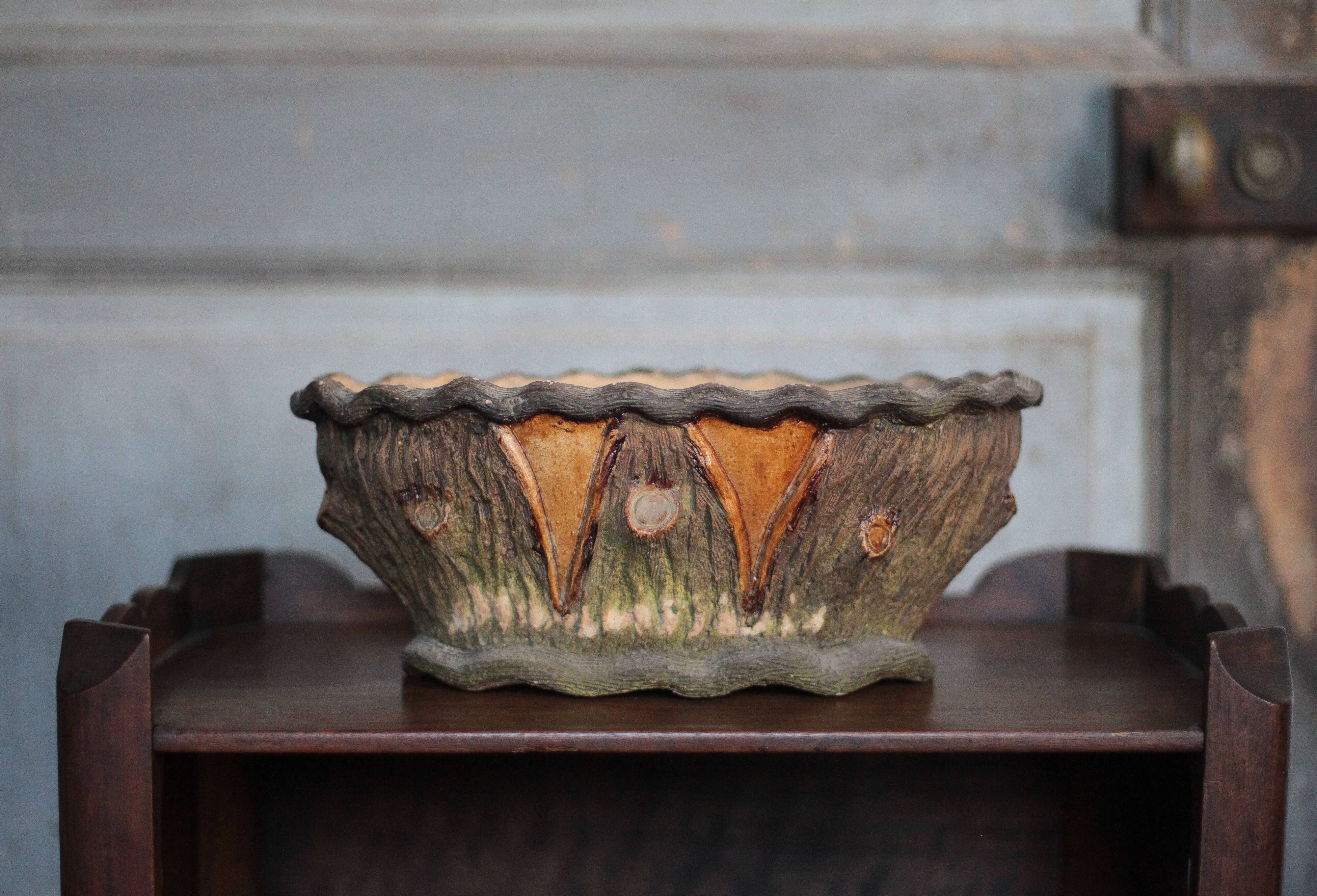 Terracotta planter in a brutalist style resembling a tree trunk, pot cover, countryside.