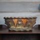 Terracotta planter in a brutalist style resembling a tree trunk, pot cover, countryside.