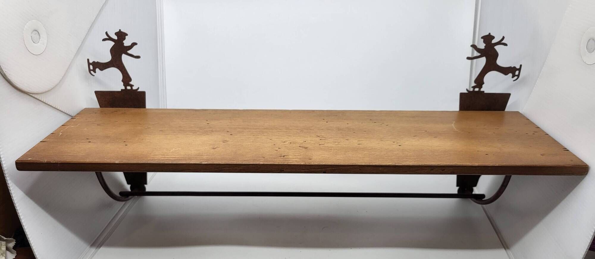 Wall shelf in wood and metal with a decoration of ice skaters.