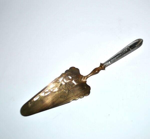 Antique silver-plated pie server with a brass blade decorated with roses.