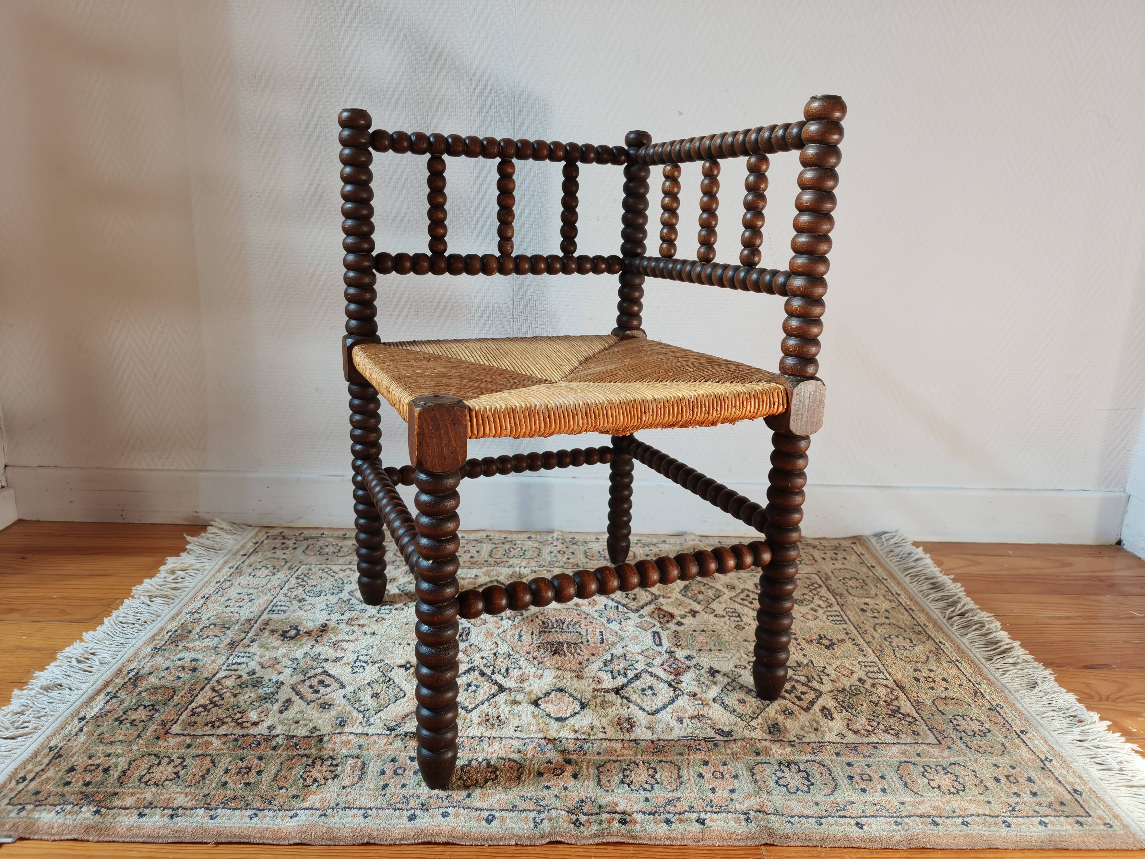 Old wooden turned spindle fireside chair with a straw seat.
