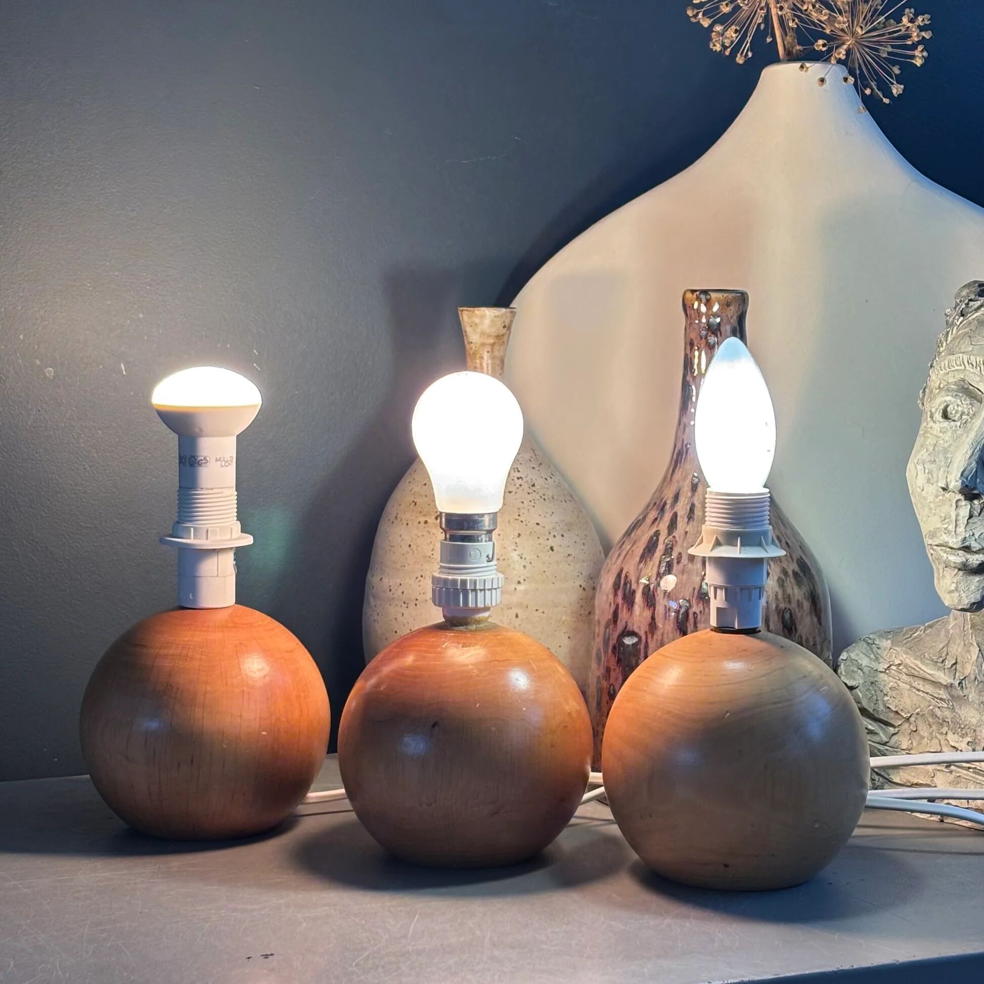 Three wooden ball-shaped lamp stands in light wood.