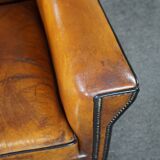 Art deco armchair in sheepskin with black piping and decorative nails