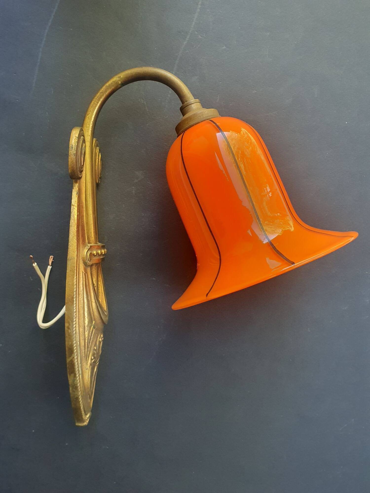 Art Deco wall light in brass with an orange globe.