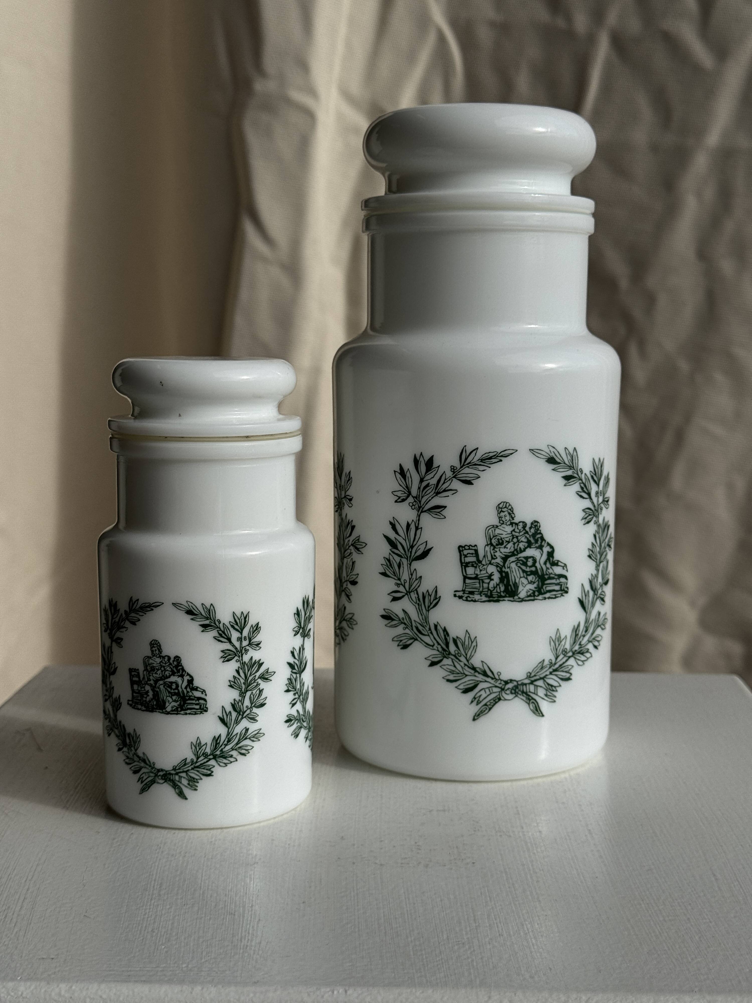 A pair of white glass bottles with Italian green patterns.