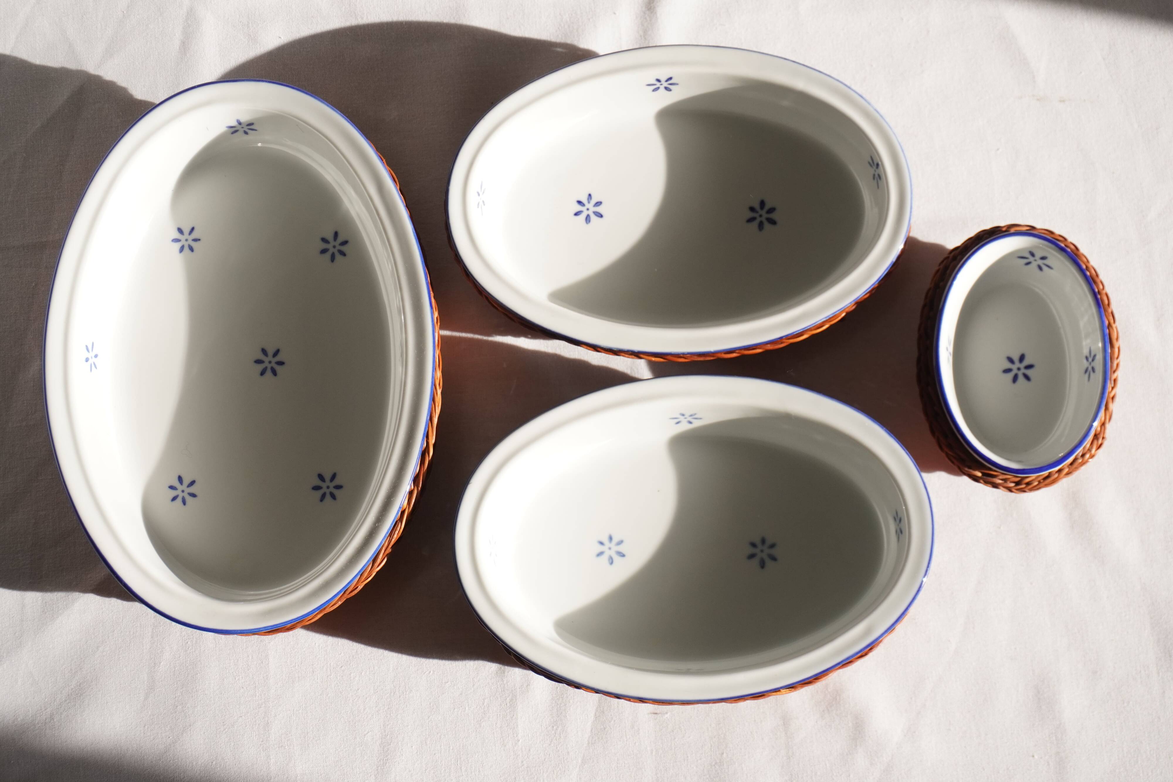 Set of 4 white porcelain dishes with blue decorations and wicker stands