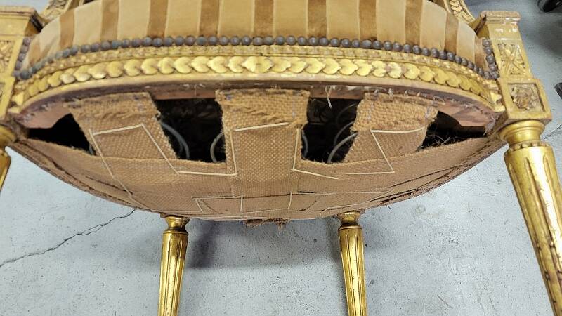 A pair of gilded wooden armchairs in the Louis XVI style.