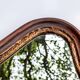 Antique wall mirror in carved wood with a wavy shape and a golden trim.