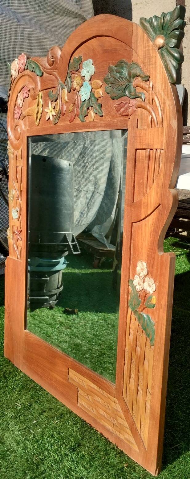 Pretty beveled mirror with wooden frame and floral decoration.