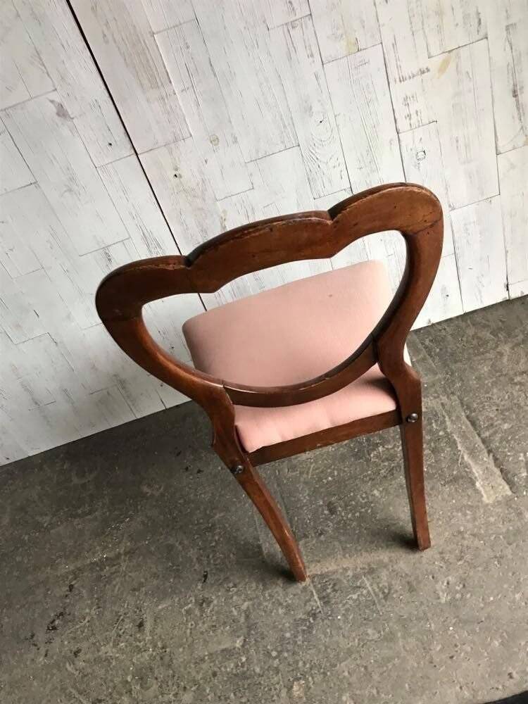 Fauteuil ancien en tissu rose et bois, dossier ajouré en cœur, pieds tournés