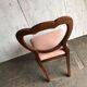 Fauteuil ancien en tissu rose et bois, dossier ajouré en cœur, pieds tournés