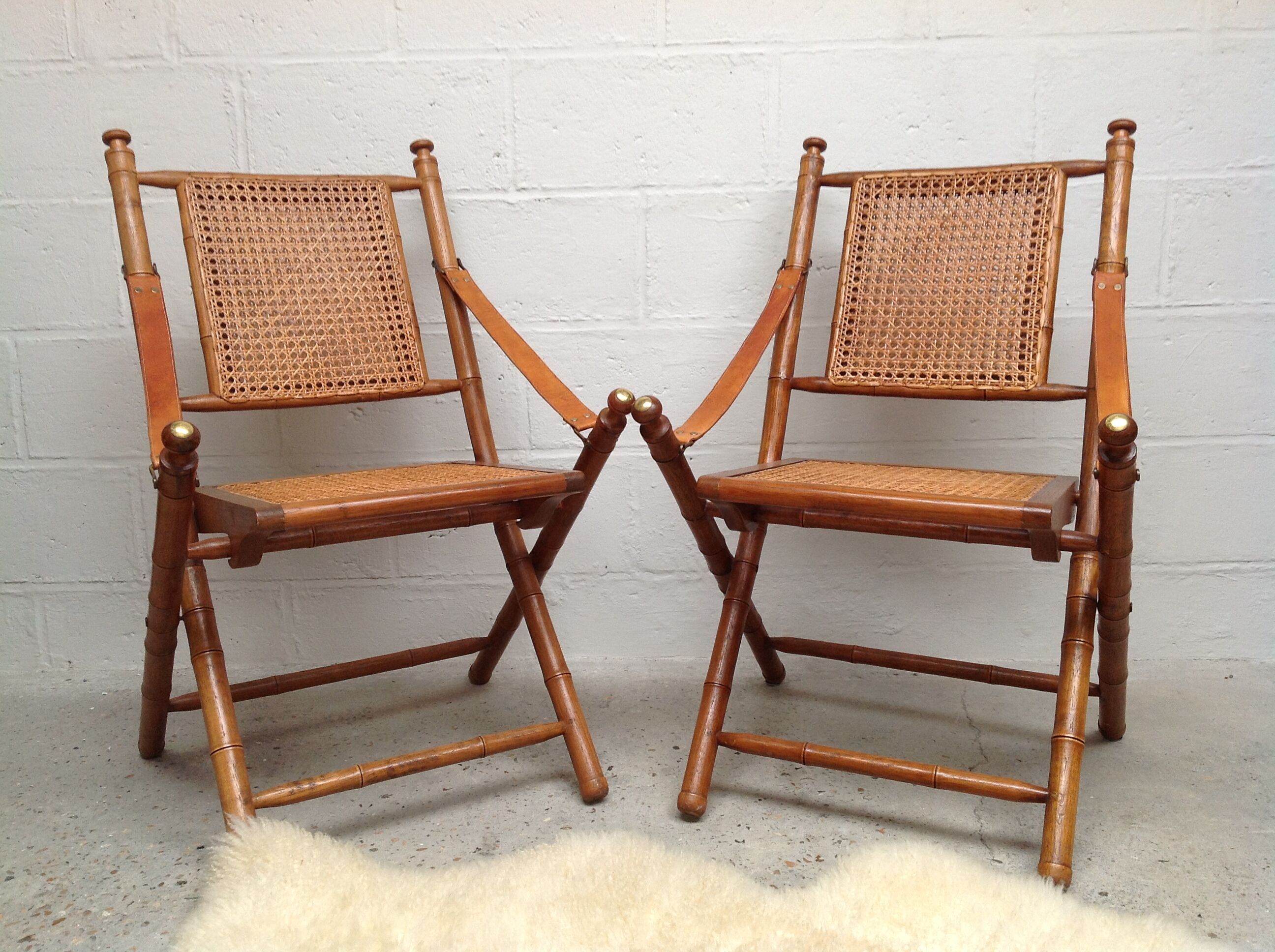 Pair of folding chairs in bamboo and caning, leather and brass