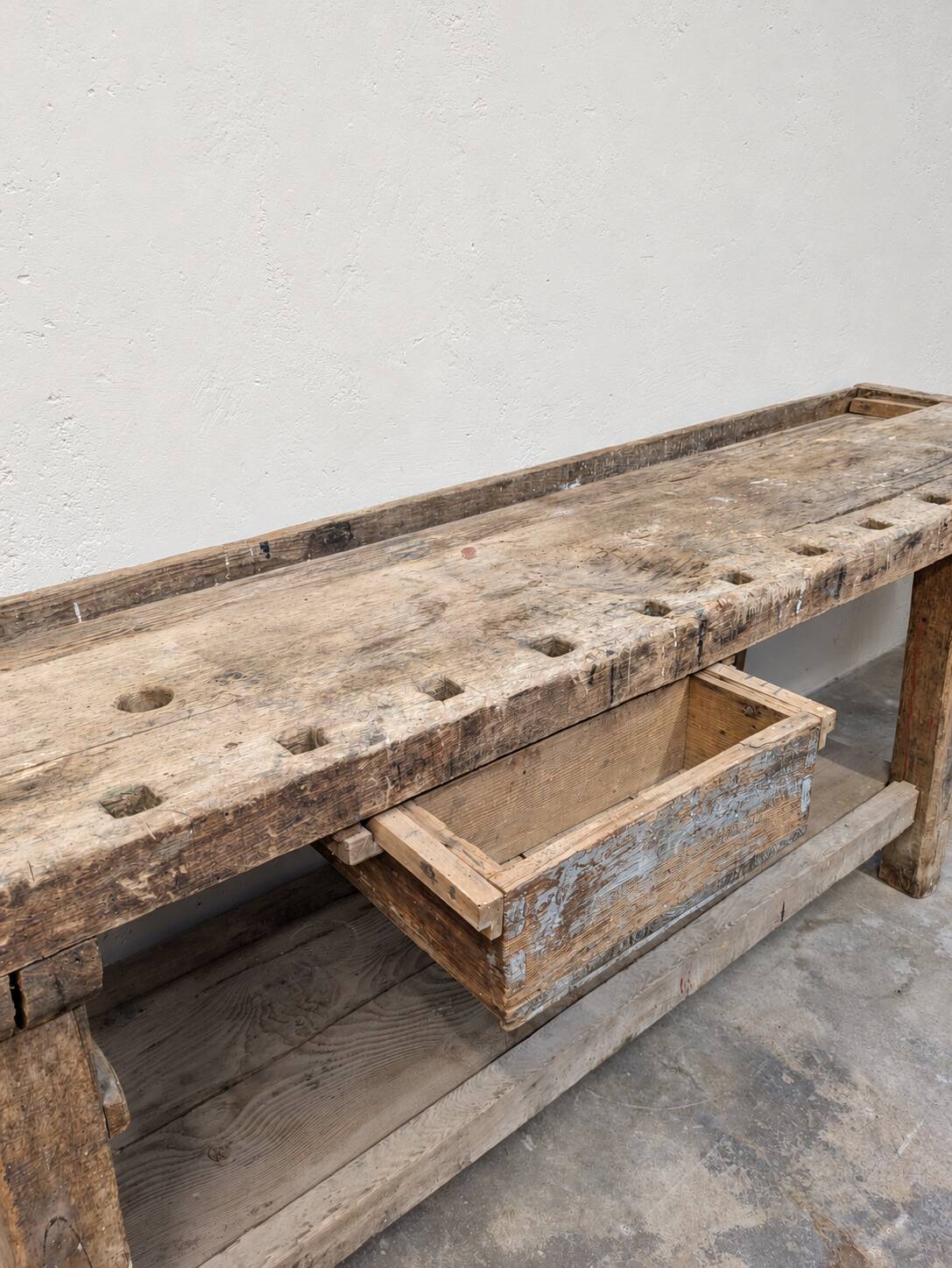 Antique wooden workbench with a vice and drawer.