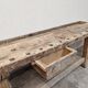Antique wooden workbench with a vice and drawer.