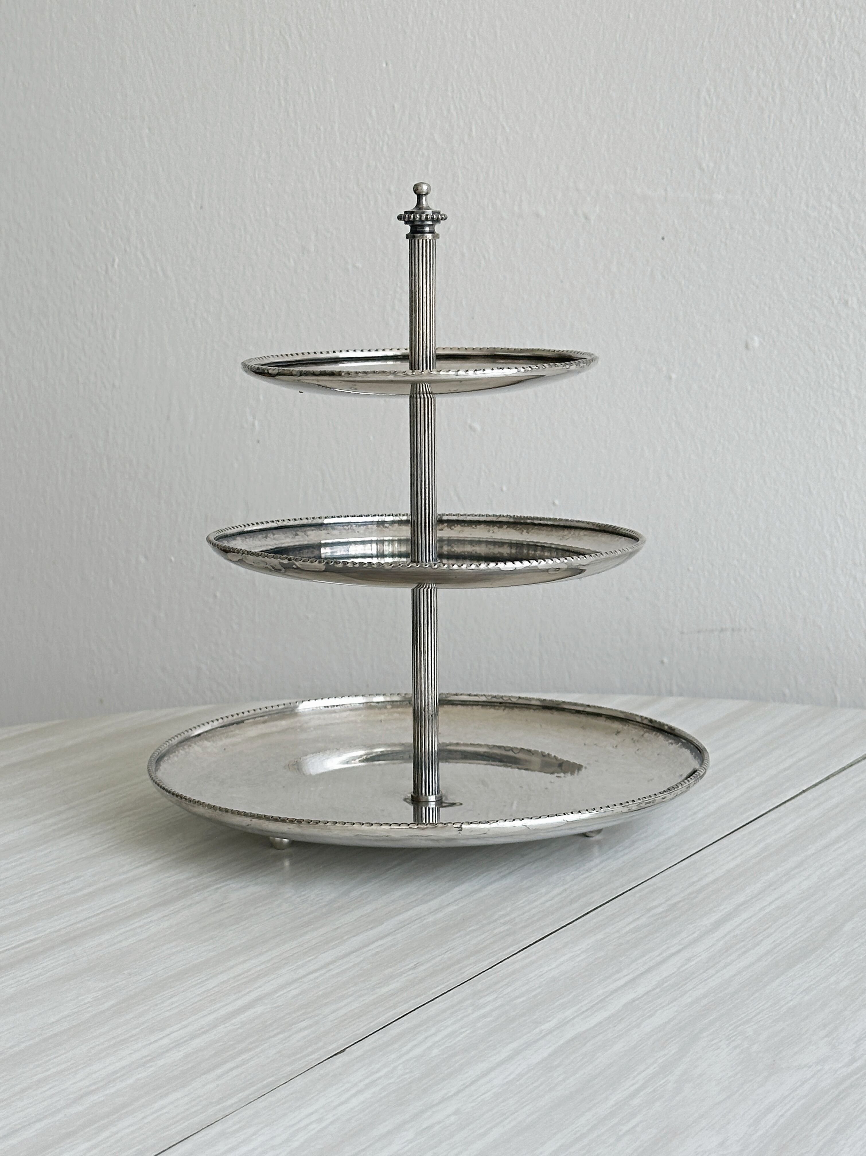 Vintage three-tiered serving stand in patinated silver metal.