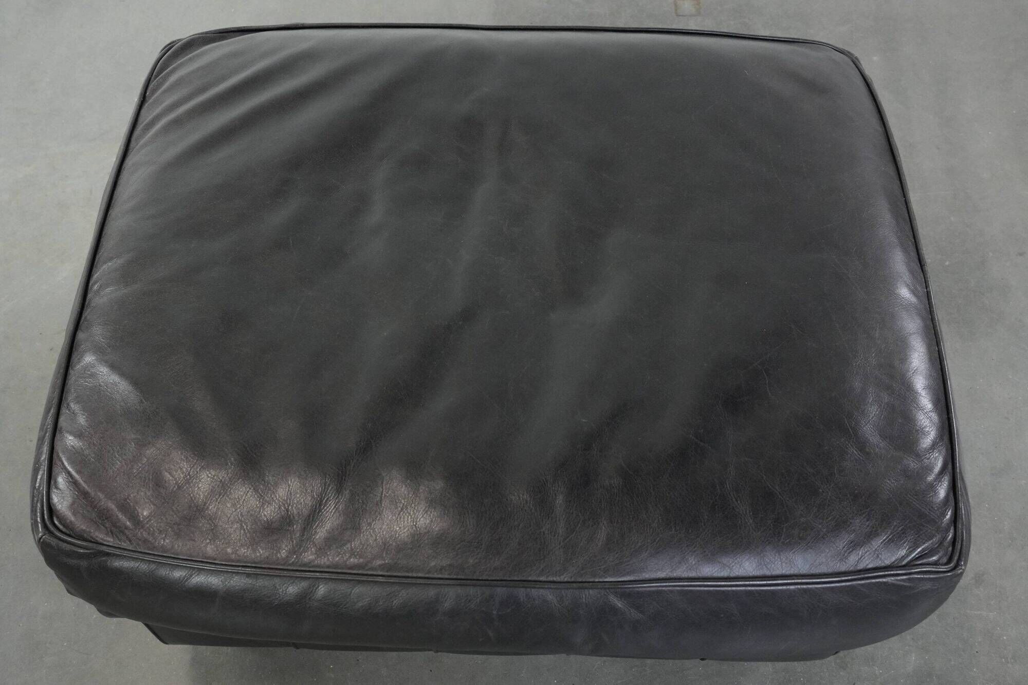 Set of a black cowhide leather Chesterfield armchair and matching ottoman