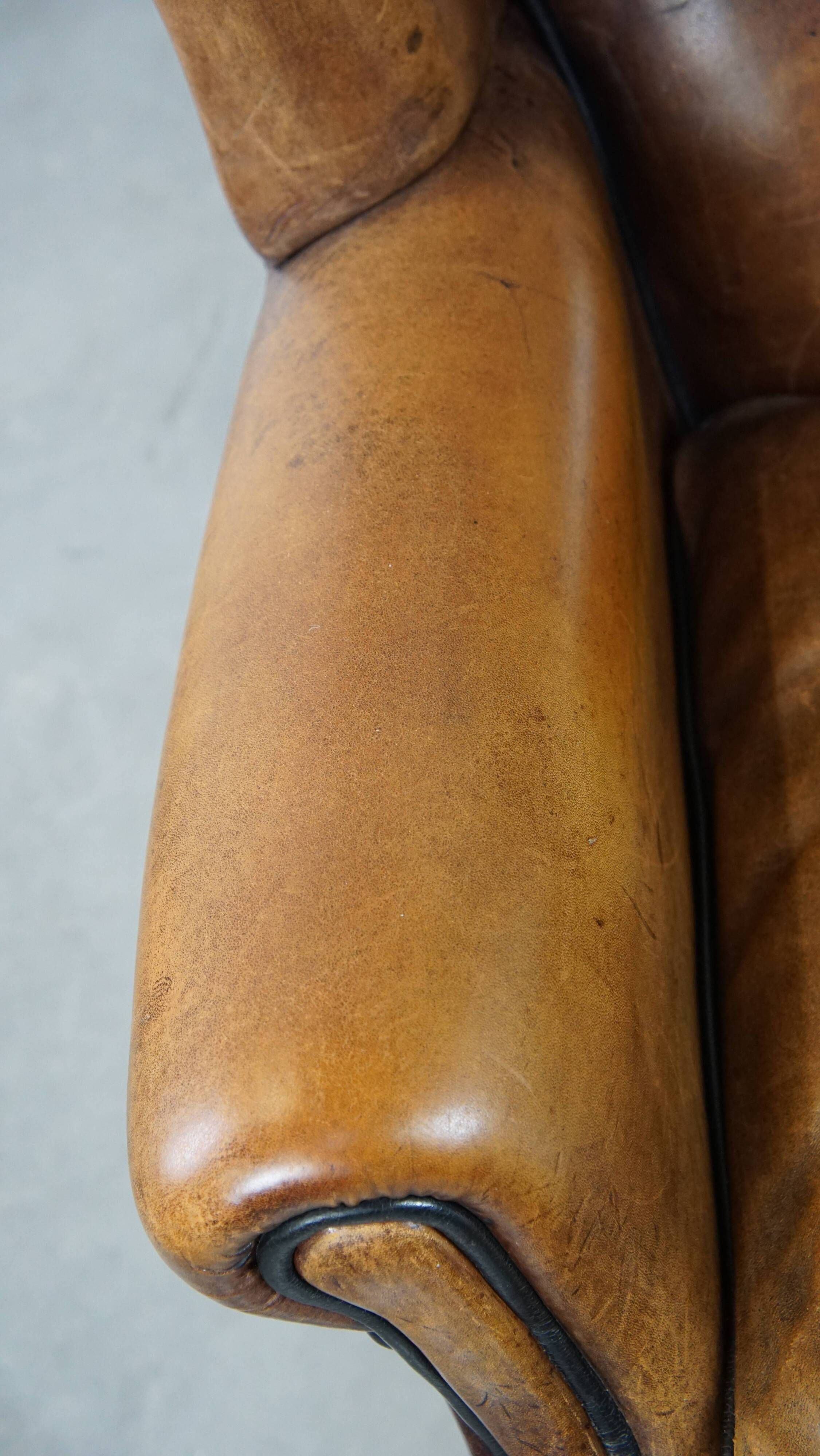 Cognac-colored sheep leather wingback chair finished with black piping