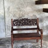Small antique Indonesian bench in carved teak with plant and floral motifs.
