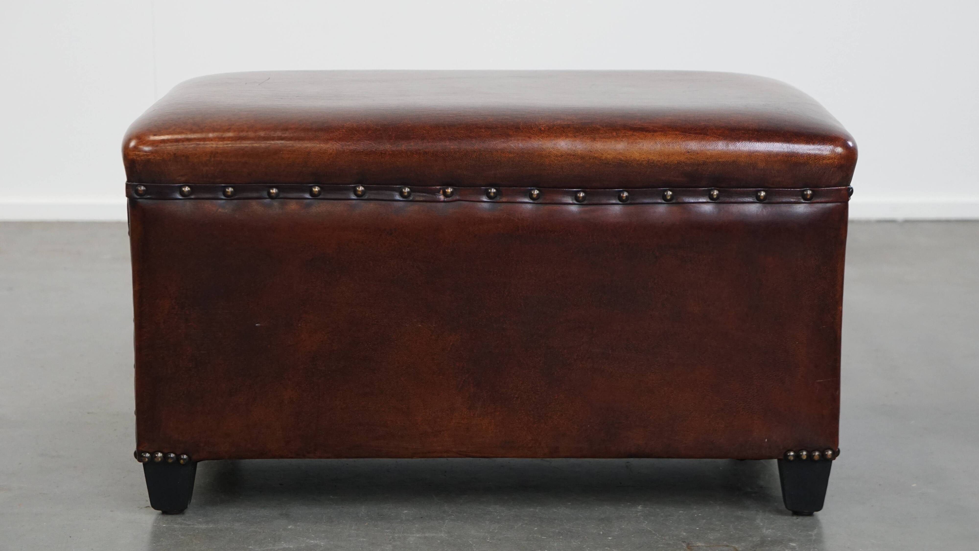 Cognac-colored sheepskin stool with decorative studs