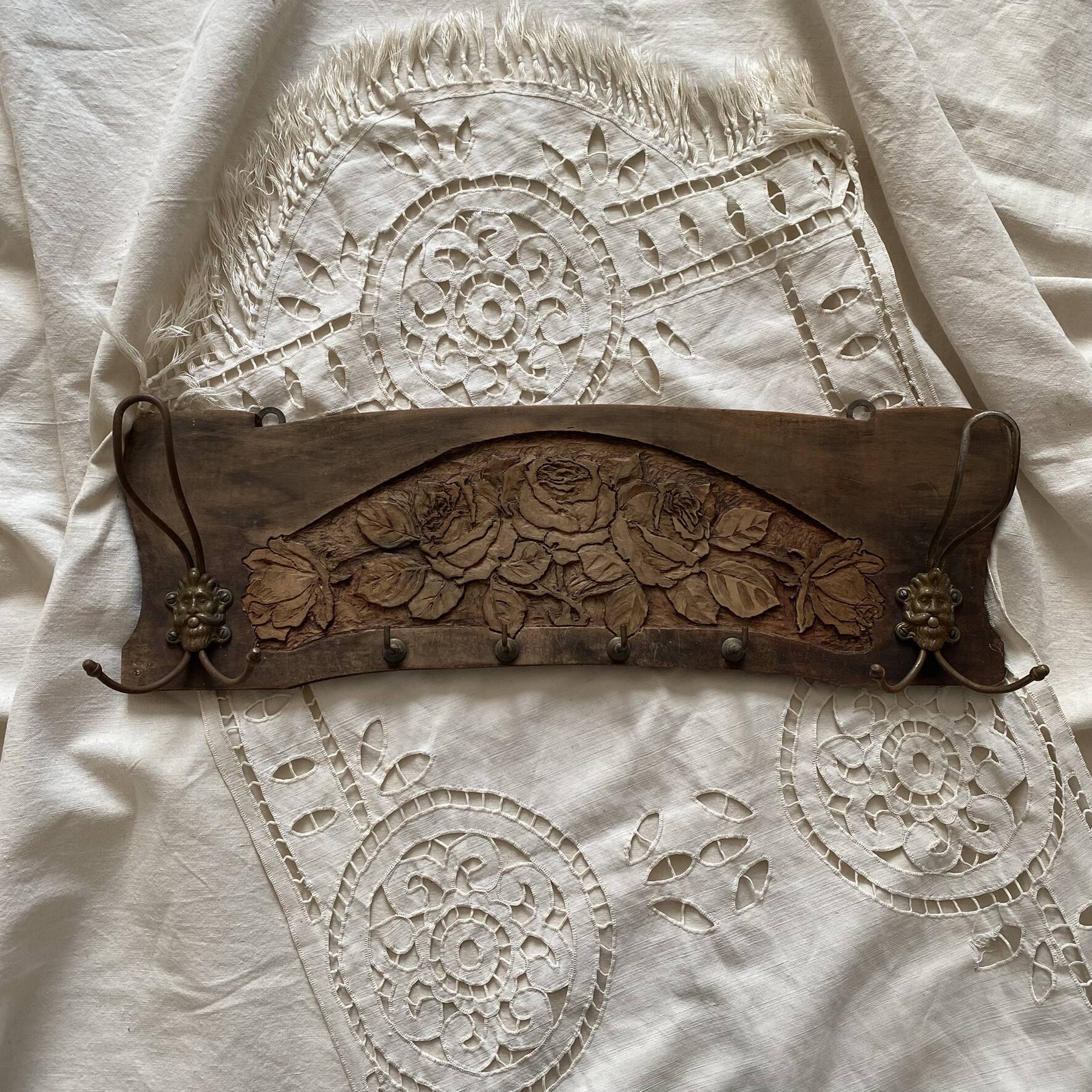 Wall-mounted coat rack in carved wood with rose decoration.