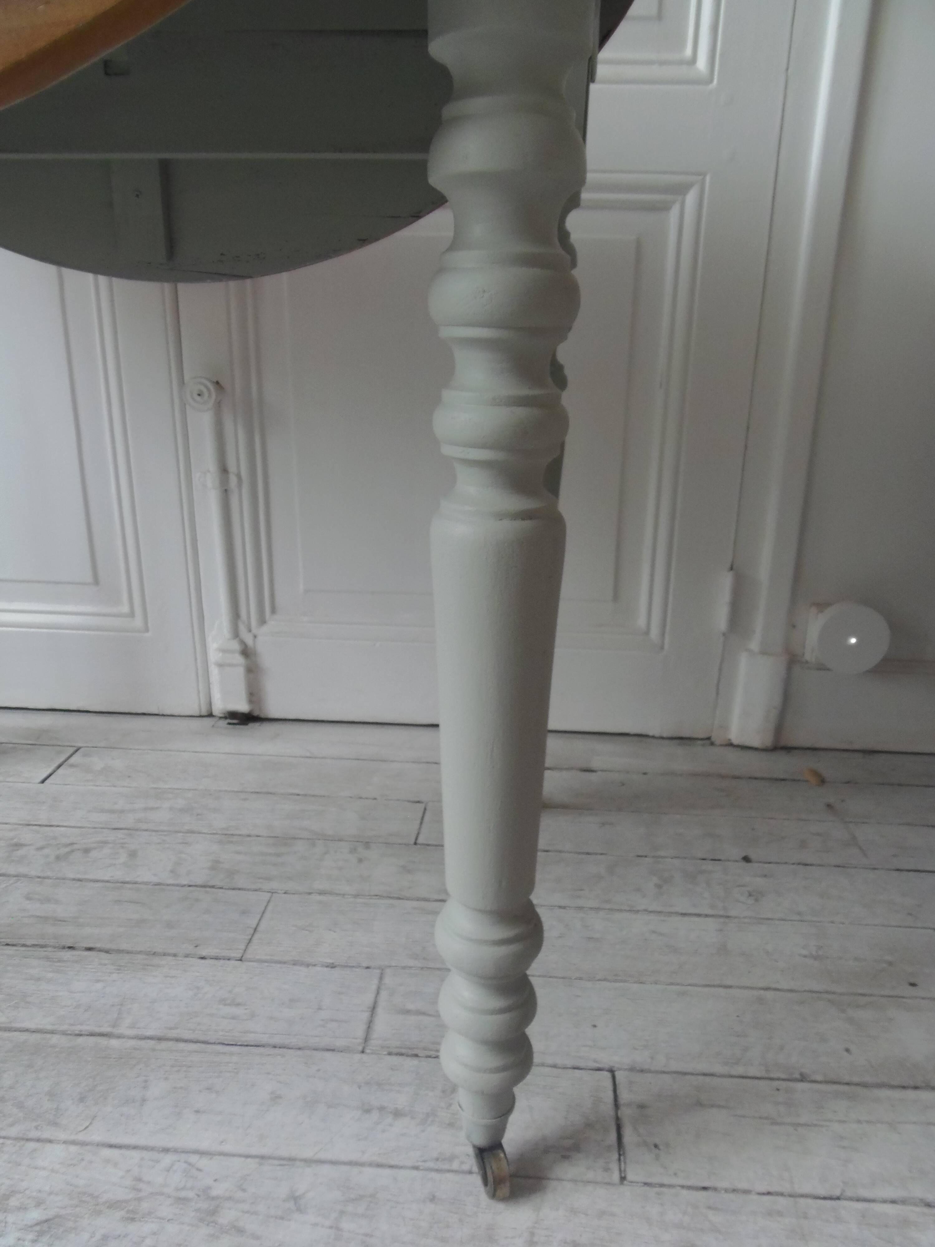 Raised walnut table with drop-leaf top, base on verdigris castors.