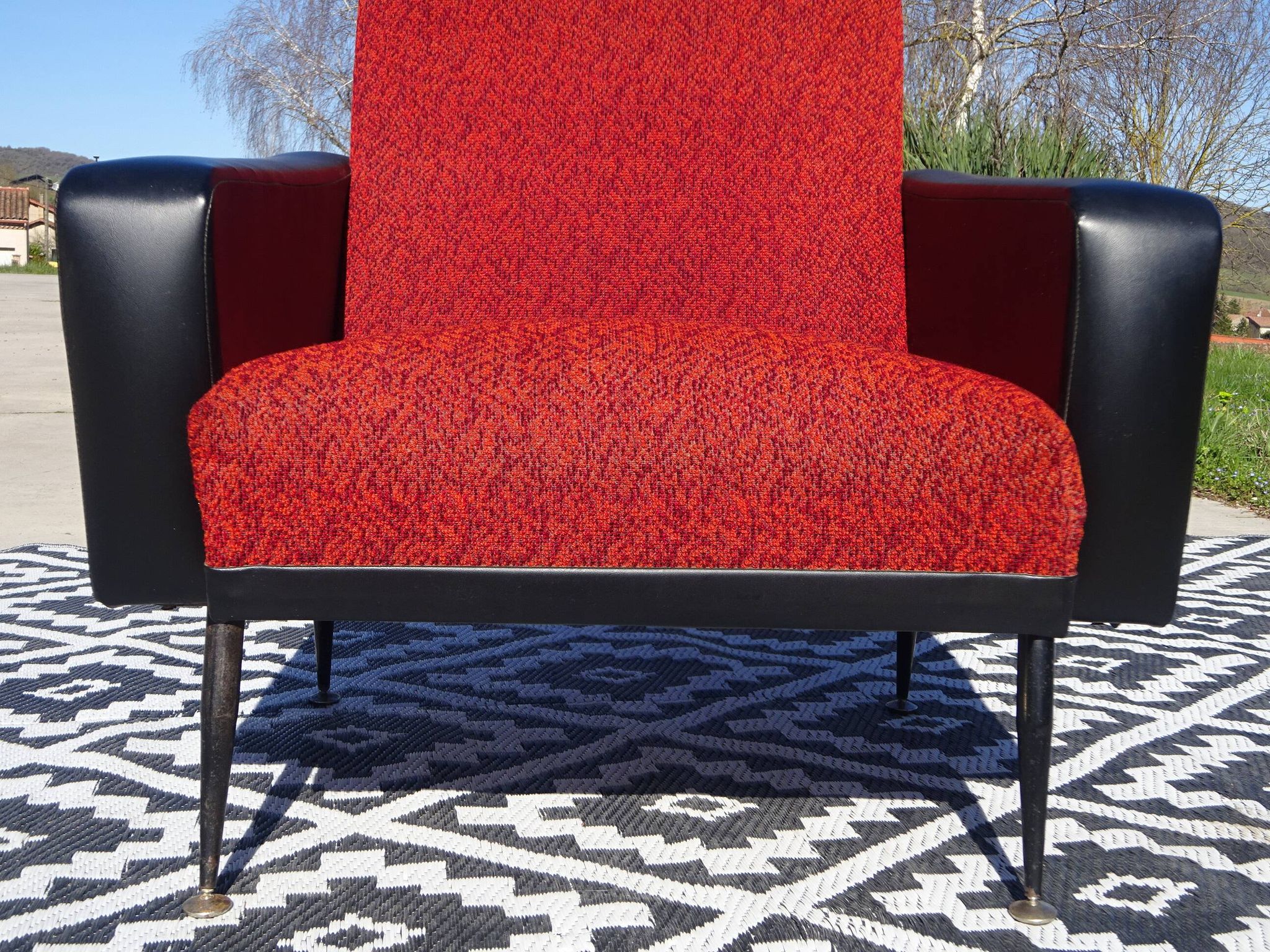 Pair of vintage armchairs in black faux leather and red fabric.