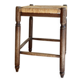 Antique square wooden stool with a woven straw seat.