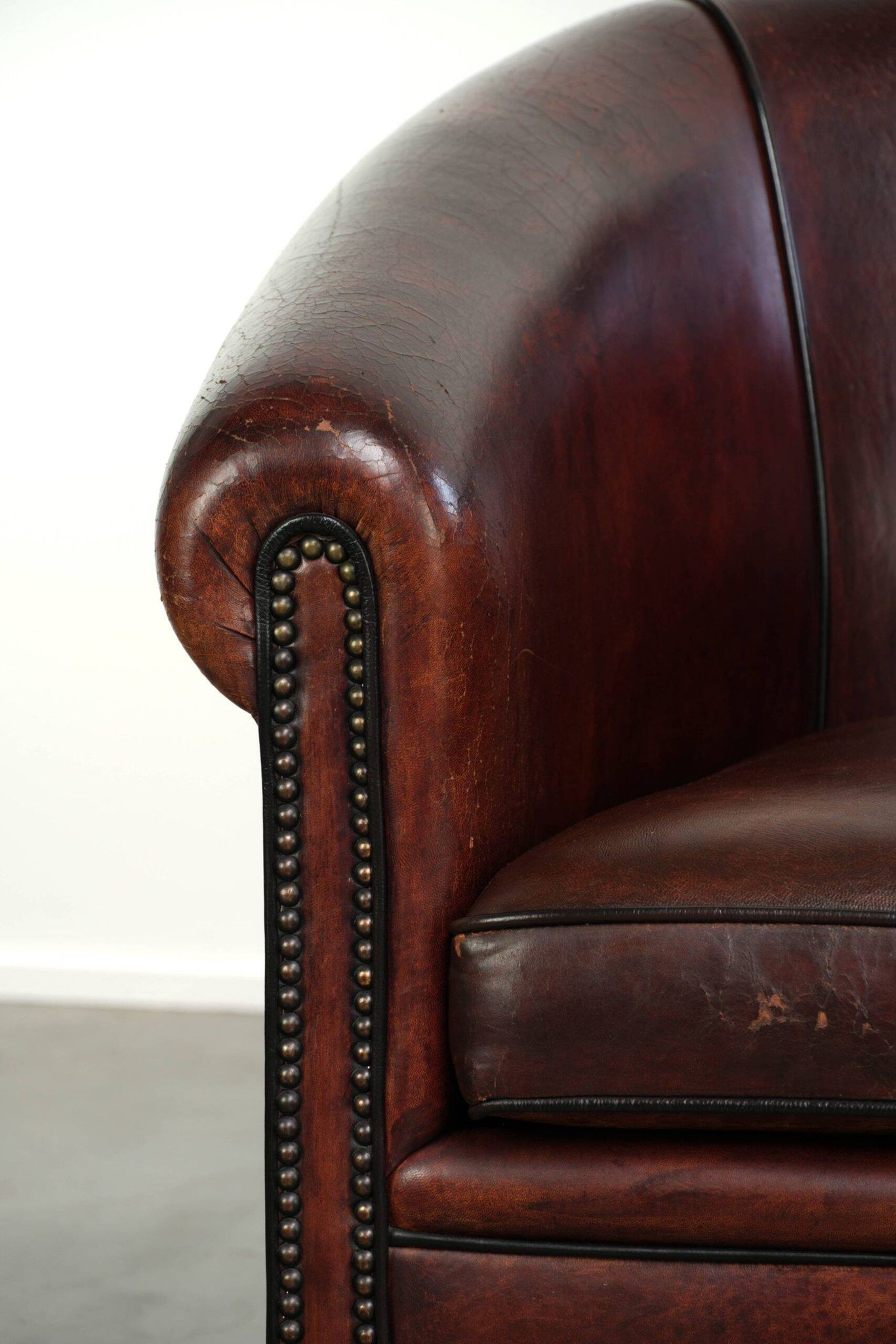 Vintage sheepskin club armchair with decorative nails and black piping