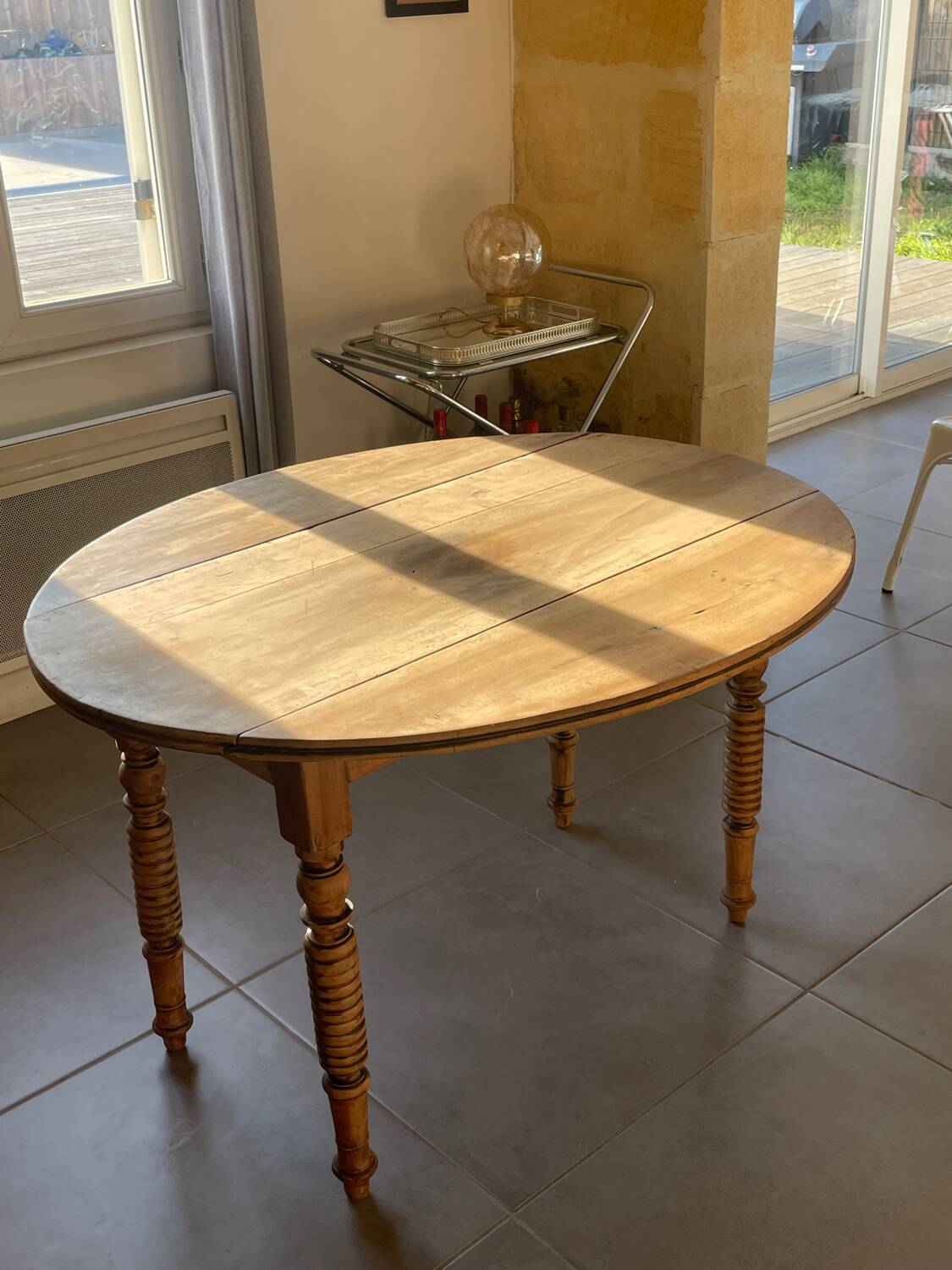Oval wooden table with drop-leaf edges.