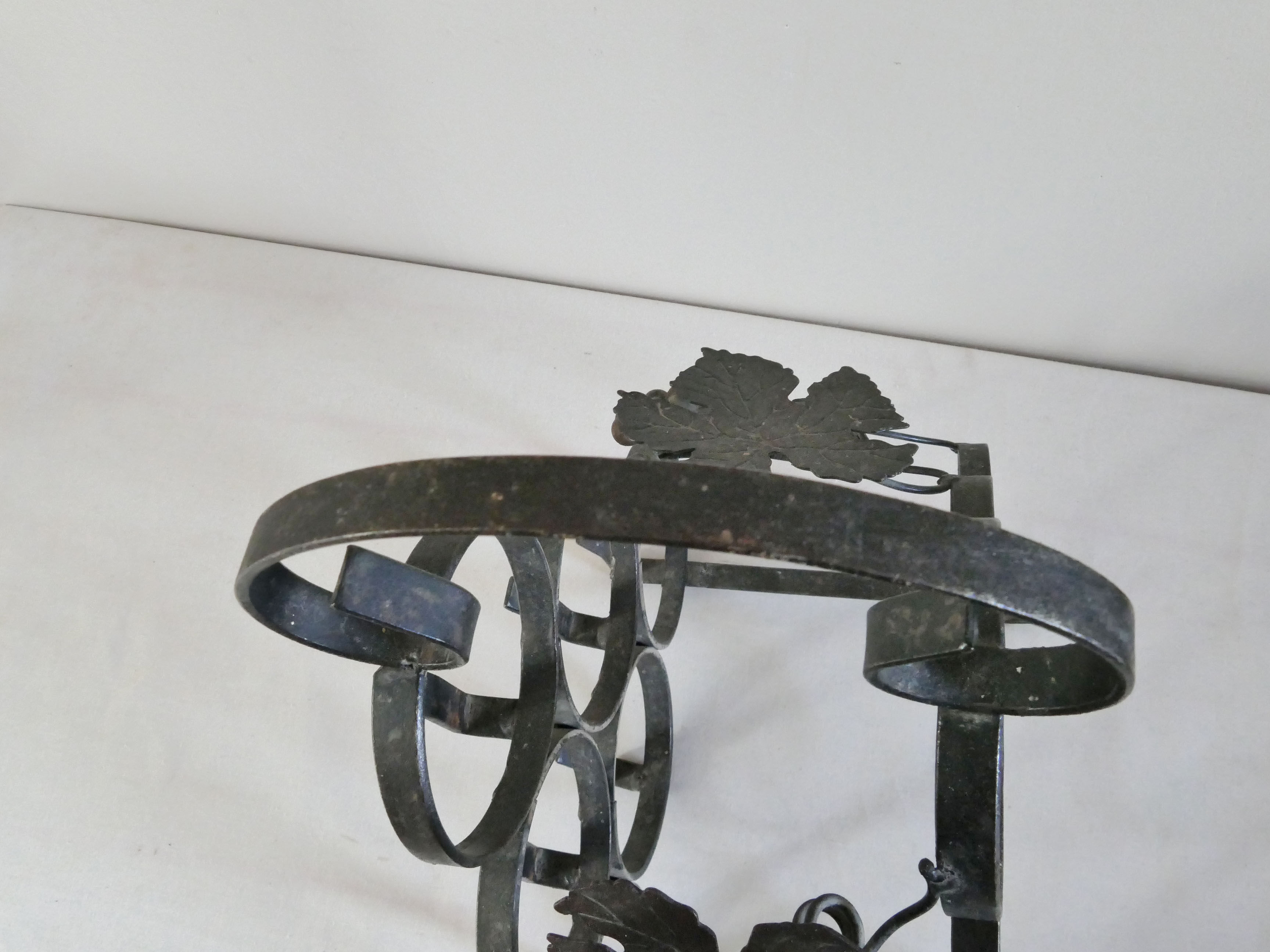 Vintage black wrought iron bottle holder decorated with vine leaves